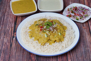Dal Chawal with the bowl of dal, raita and salad on a wooden background