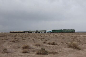 Desert Train Journey Through Arid Wilderness Landscape Under Cloudy Sky