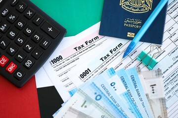 United Arab Emirates dirham money bills and calculator with tax form on flag. Taxation and...