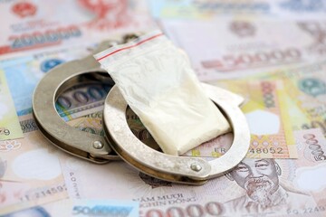 Vietnamese dong currency money bills and cocaine pack with handcuffs. The concept of drug crimes