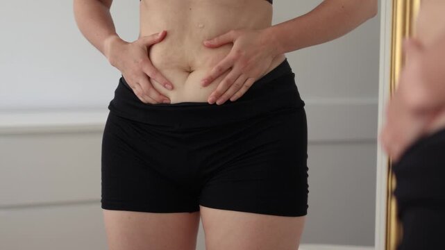 Individual engages in mindful movement exercises to address bloating and stomach discomfort. Focus is on relaxation and body awareness in a home setting.