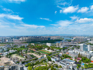 Ningbo city, China, offers an expansive aerial view of its modern buildings, green areas, and a peaceful lake under a bright blue sky.