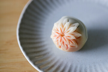 A piece of delicious Japanese confectionery on off white ceramic plate on wooden table.
