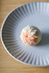 A piece of delicious Japanese confectionery on off white ceramic plate on wooden table.