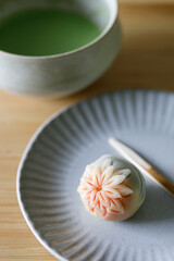 Cup of fresh matcha tea, green tea and Nerikiri, Japanese confectionery, on wooden table.