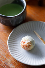 Cup of fresh matcha tea, green tea and Nerikiri, Japanese confectionery, on wooden table.