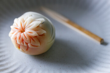 A piece of delicious Japanese confectionery on off white ceramic plate on wooden table.