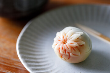 A piece of delicious Japanese confectionery on off white ceramic plate on wooden table.