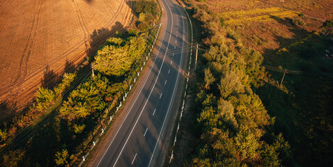 Winding road through autumn landscape at sunset, aerial view