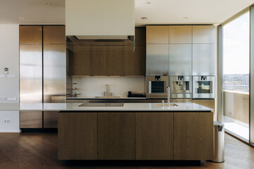 A modern kitchen that features a sleek design along with abundant natural light flooding in