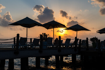 Beach umbrellas on a pier against the backdrop of the rising sun on a summer morning in the Turkish province of Antalya