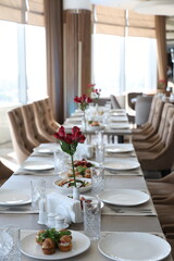 Vertical photo of formal dining table with appetizers and floral decor in sunlit room