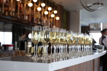 Champagne flutes and bottle on white counter at festive gathering
