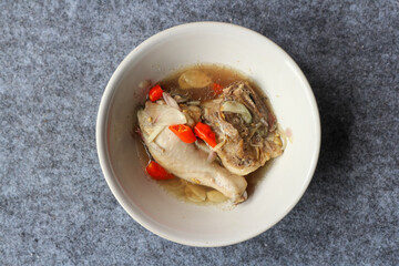 Steamed chicken served in a bowl with various herbs and spices