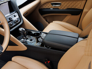 Premium vehicle interior featuring tan perforated leather seats, quilted door panels and chrome-accented console