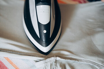A close-up of an iron on a neatly laid out shirt fabric, highlighting the simple task of ironing clothes at home.