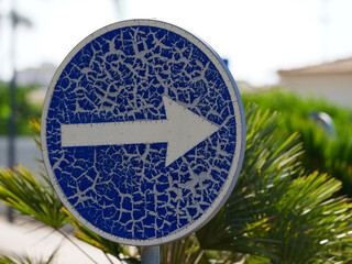 blue traffic sign, prescribed direction of travel right, cracked surface, weather influences,