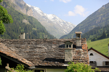 Scenic alpine village with wooden barns, green valley and mountain forest in Switzerland