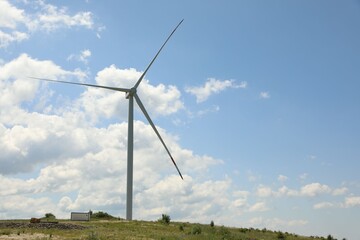 Modern wind turbine in field on sunny day. Space for text