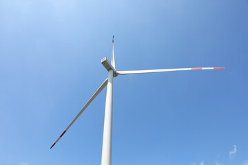 Fototapeta premium Modern wind turbine against blue sky, low angle view