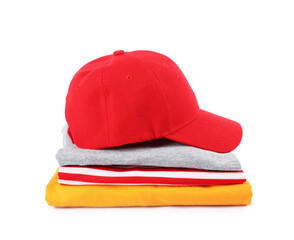 Red baseball cap and stack of folded t-shirts isolated on white. Mockup for design