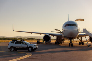 Airport security vehicle assists at the tarmac as a plane prepares for boarding during sunset