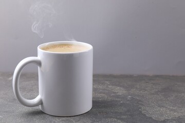 Aromatic coffee in cup on grey textured table, closeup. Space for text