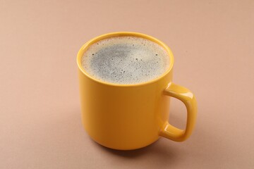 Aromatic coffee in cup on beige background, closeup