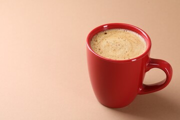 Aromatic coffee in cup on beige background, closeup. Space for text