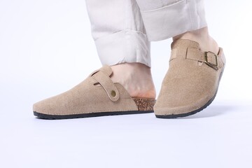 Woman in stylish beige slippers on white background, closeup