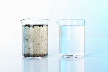 Glass beakers with clean and dirty water on mirror surface