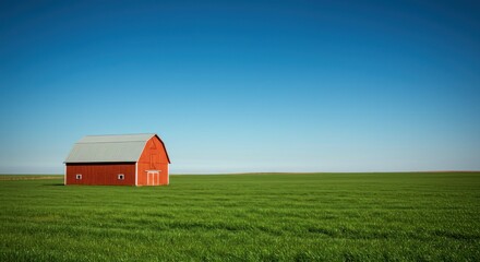 A vibrant red structure sits alone in a vast, green field, under a crisp, cloudless, light blue sky. Minimalist, pastoral scene