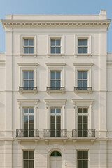 Elegant Neoclassical White Stone Facade of a Historic Residential Building, Showcasing Symmetrical Windows and Ornate Balconies in a Classic Urban Setting.