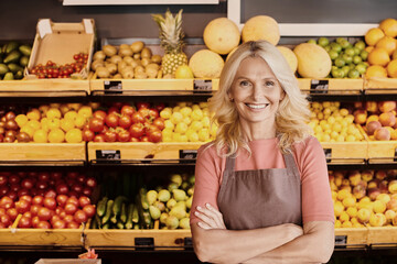 Blonde saleswoman offers fresh organic produce in vibrant grocery store