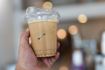 Cold brewed ice latte coffee on plastic cup in man hand at cafe