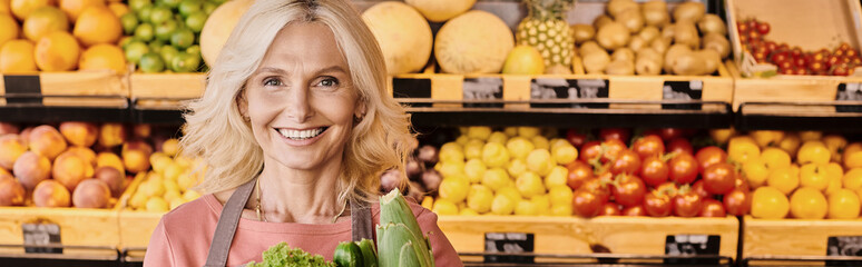 Blonde saleswoman offers fresh local produce at a modern grocery store