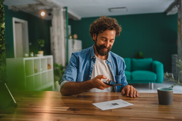 Freelancer scanning qr code with smart phone at home office