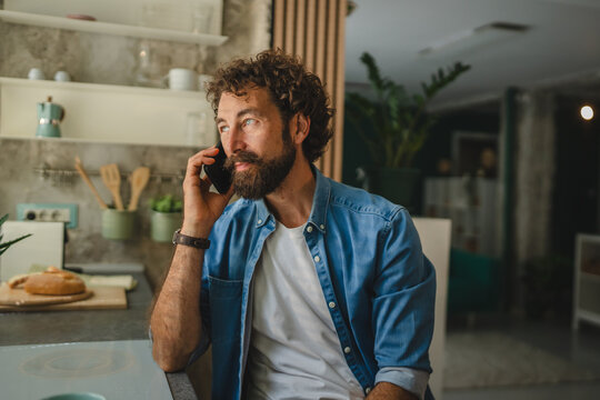 Freelancer talking on mobile phone at home in kitchen