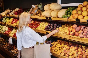 Blonde woman exploring organic produce at a modern grocery store