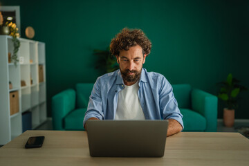 Focused freelancer working on laptop in home office