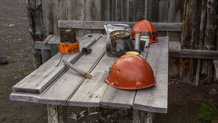 Industrial workbench featuring orange safety helmets, tools, and a coffee pot, set against a rustic...