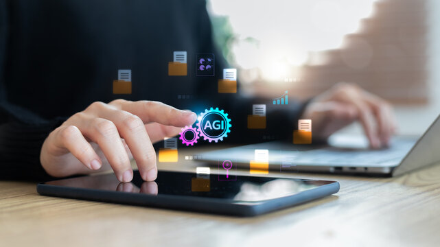 Close-up finger touching AGI icon on digital screen with data files and charts. Concept of Artificial General Intelligence and smart data processing.