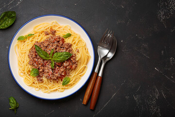 Delicious spaghetti bolognese garnished with fresh basil and grated parmesan, served on a white...