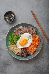 Bibimbap, authentic korean dish with a steamed rice topped with fried egg, beef, colorful...