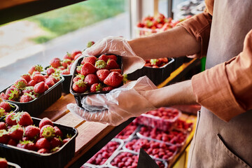 Salesman showcasing fresh strawberries at a modern grocery store