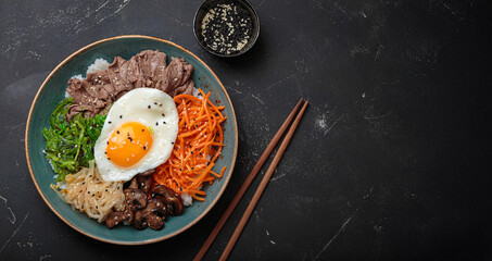 Bibimbap, authentic korean dish with a steamed rice topped with fried egg, beef, colorful...