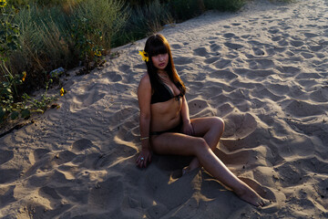 Young Woman Wanders Beach Path sits in Black Bikini