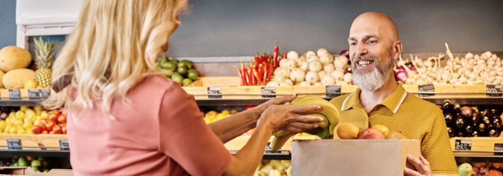 Customer engages with salesperson for fresh organic produce in vibrant grocery store