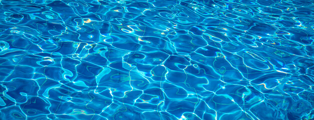 Sunlight reflecting on the rippling water surface of a swimming pool creates a beautiful and mesmerizing pattern of light and shadow, perfect for backgrounds and summer-themed projects