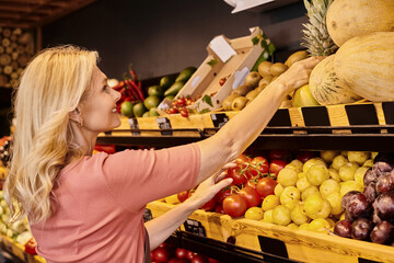 Blonde saleswoman showcases organic produce in modern grocery store setting